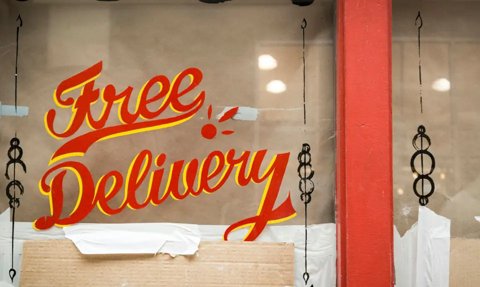 Red script lettering with a yellow shade line, painted on a shop window.