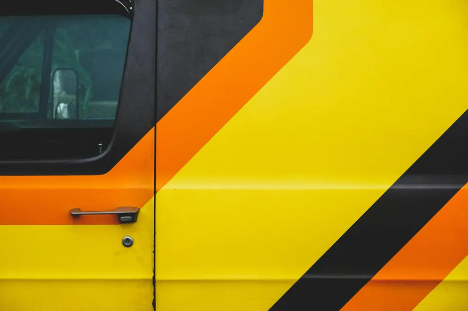 Orange and black stripes on a yellow van, crossing the door and its handle.