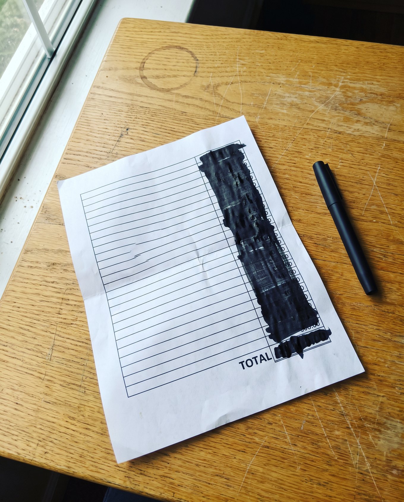 A printed quotation on a desk with the entire amounts column struck out in black marker. Only the word TOTAL is still readable.